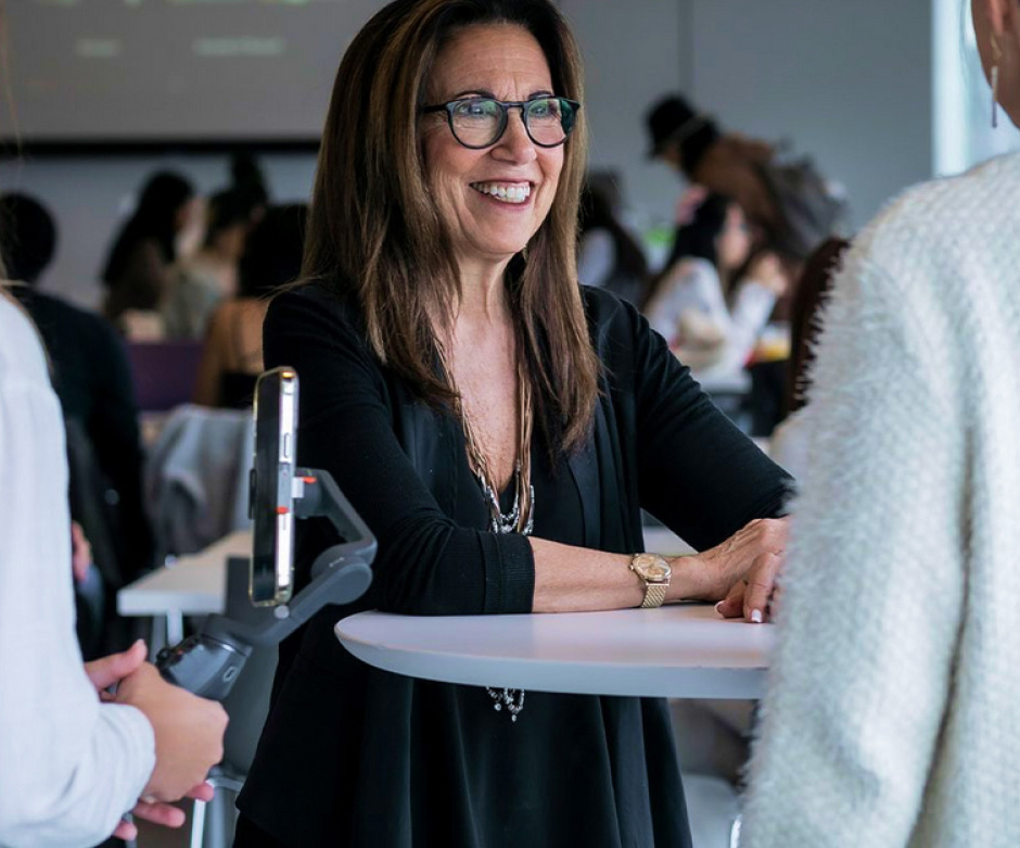 Dr. Judith Spitz speaks with students at a table during an event.